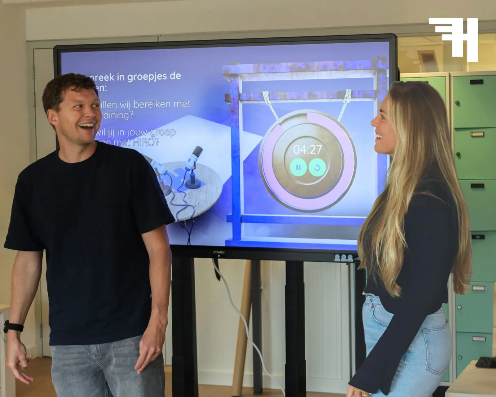 Twee trainers van HiRO in gesprek voor een digibord tijdens een training