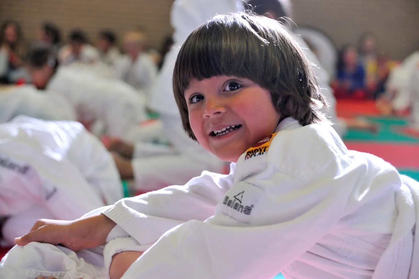Lachende kleuter in judopak op de mat