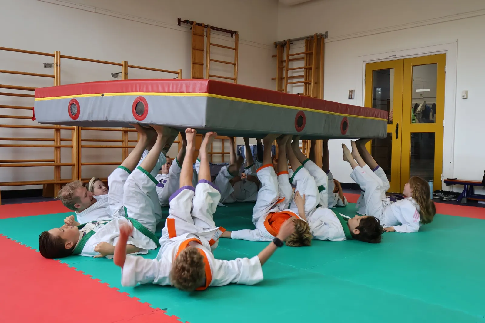 Kinderen kruipen lachend onder de judomat door